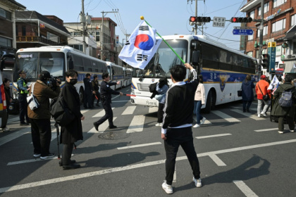 A man waves a South Korean flag as police buses block the road in front of the Constitutional Court days ahead of the long-awaited ruling on president Yoon Suk Yeol's impeachment