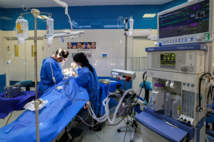 Iranian surgeon Hamidreza Hosnani and an assistant perform surgery at his private clinic in Tehran