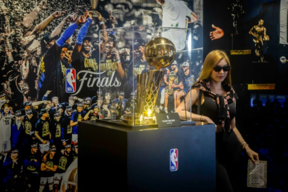A tourist poses next to the NBA Championship trophy at the Venetian's NBA House in Macau - Eduardo Leal (AFP)
