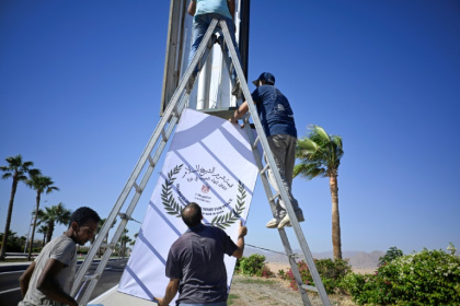 Municipal workers hang a sign advertising the upcoming US- and Egyptian-hosted Gaza peace summit in Sharm el-Sheikh - Khaled DESOUKI (AFP)