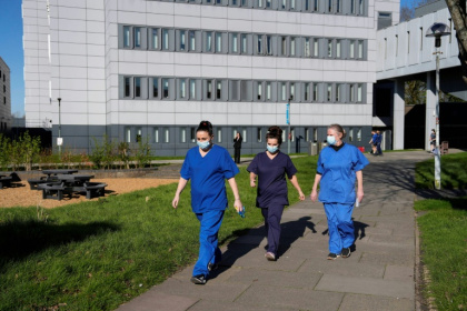 People wearing medical scrubs and face masks walk across campus at the University of Kent in Canterbury which is the centre of a deadly, unprecedented outbreak of meningitis - CARLOS JASSO (AFP)