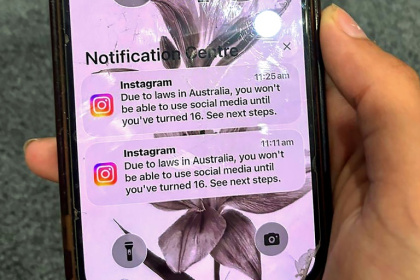 A teenager holds a phone displaying a message from social media platform Instagram after the account was locked for age verification in Australia - STR (AFP)